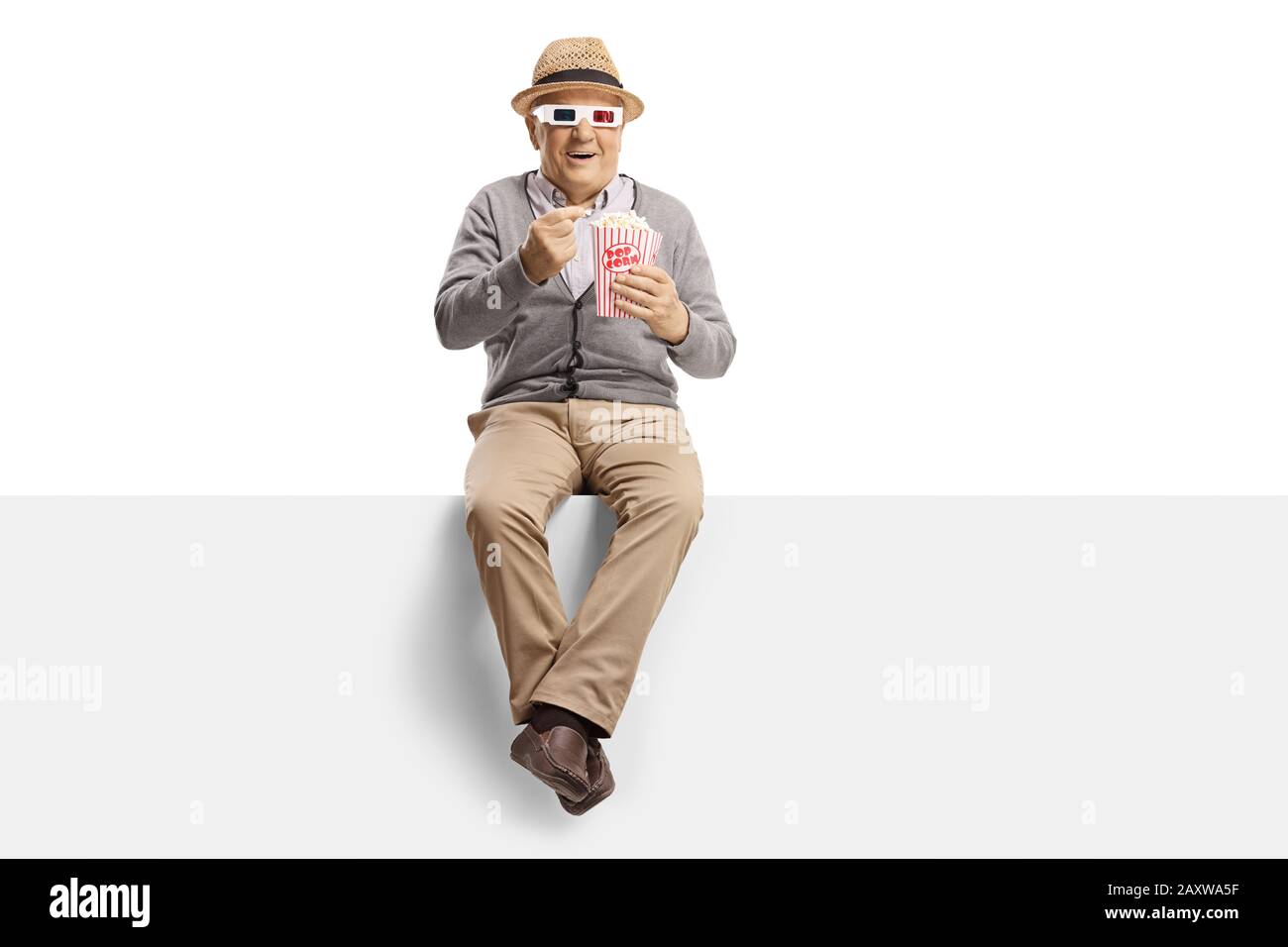 Älterer Mann sitzt auf einem Panel, der Popcorn isst und einen Film mit einer 3D-Brille sieht, die auf weißem Hintergrund isoliert ist Stockfoto
