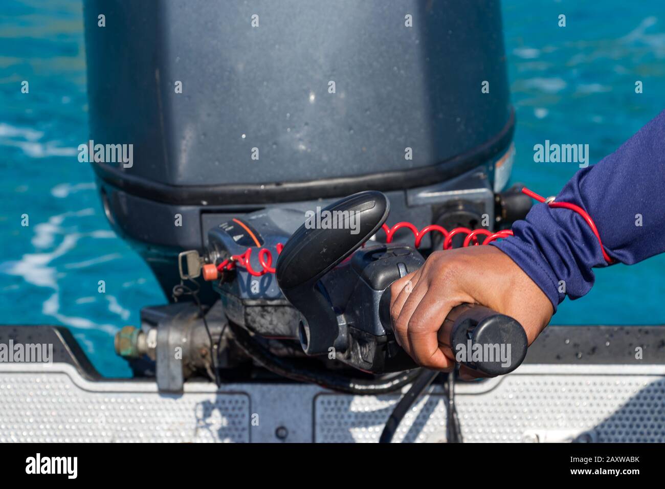 Männliche Hand, die ein aufblasbares Boot mit der Deichsel eines Außenbordmotorboots fährt. Stockfoto