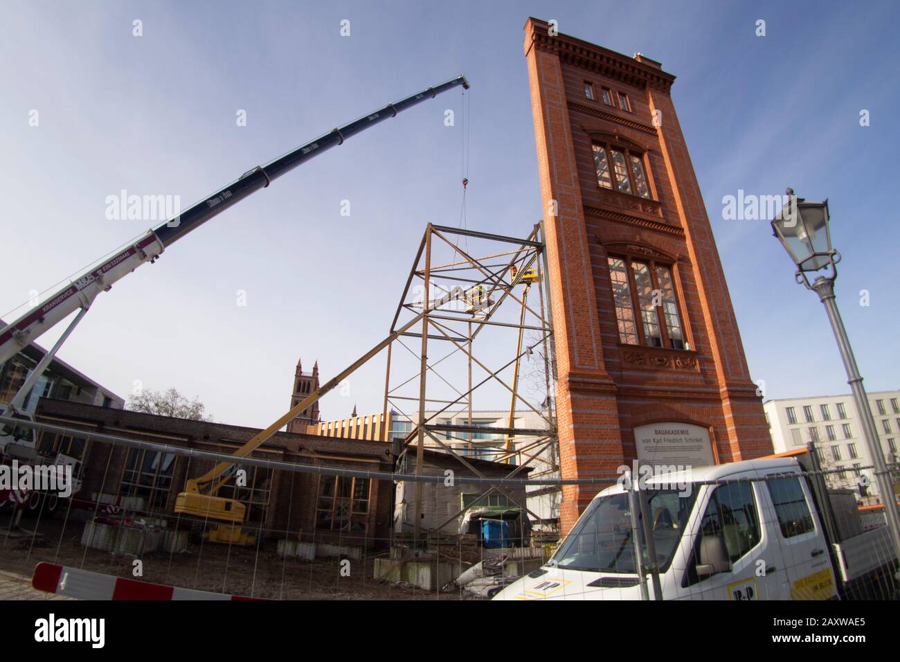 Berlin, Deutschland. Februar 2020. Auf den Resten eines Stahlgerüstes steht ein Baukran, an dem Baupläne mit der bemalten Attrappe der Bau-Akademie von Karl Friedrich Schinkel hingen. Arbeiter demontieren die Streben von Hubkränen. Das im Jahre 186 eröffnete Gebäude soll für 62 Millionen Euro umgebaut werden. Baucontoiner befinden sich direkt am Gebäude. Wann der Bau beginnen wird, ist jedoch unklar. Kredit: Paul Zinken / dpa / ZB / dpa / Alamy Live News Stockfoto