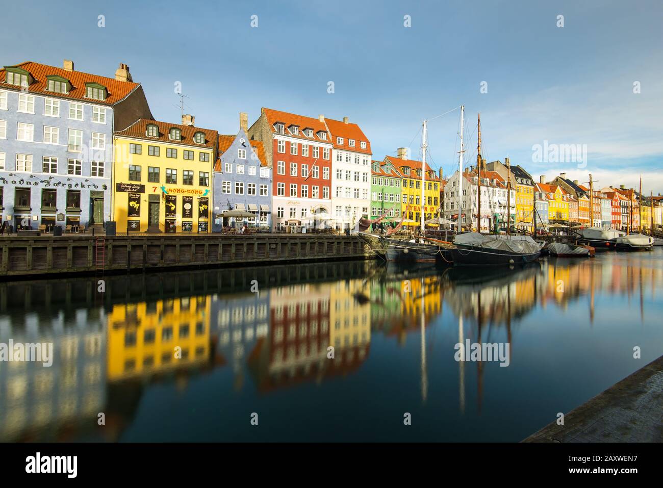 Lange Sicht auf den berühmten Nyhavn von Dänemark im Zentrum Kopenhagens mit den farbenfrohen, bemalten Gebäuden mit geparkten Booten. Stockfoto