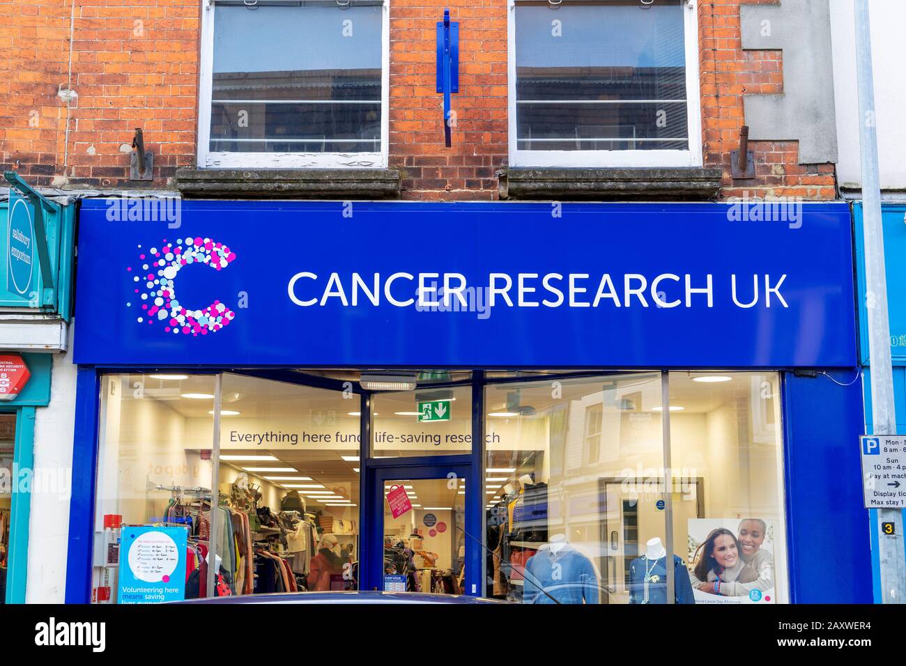 Charity-Zeichen von Cancer Research UK über dem Eingang zum Shop, in dem gespendete Gegenstände aus zweiter Hand verkauft werden Stockfoto