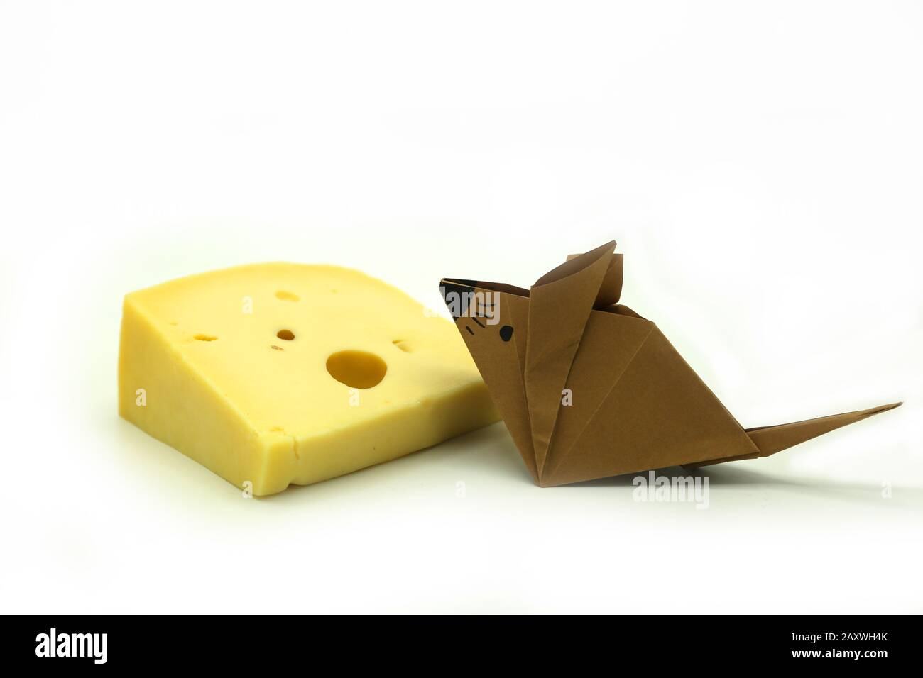 Braune Origami-Maus in der Nähe einer großen Scheibe Käse isoliert auf wihite Hintergrund. Kopierbereich. Stockfoto