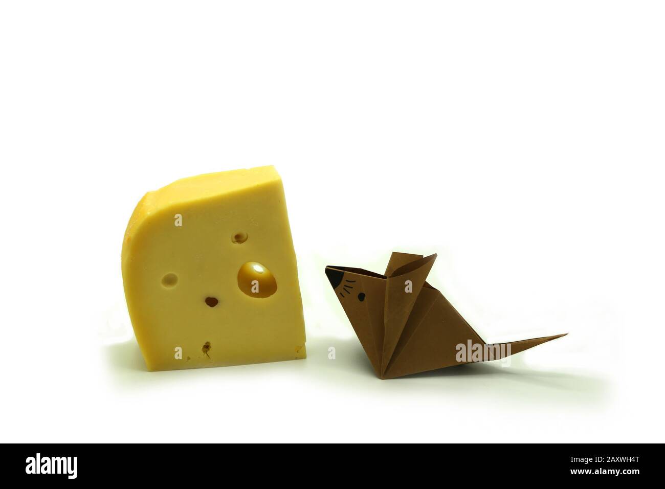 Braune Origami-Maus in der Nähe einer großen Scheibe Käse isoliert auf wihite Hintergrund. Kopierbereich. Stockfoto