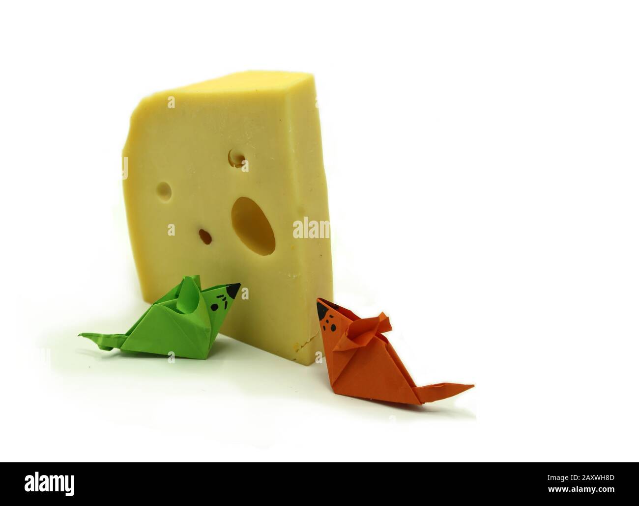 Origami-Maus mit orangefarbenem und grünem Papier in der Nähe einer großen Käsescheibe, die auf wihitem Hintergrund isoliert ist. Kopierbereich. Stockfoto