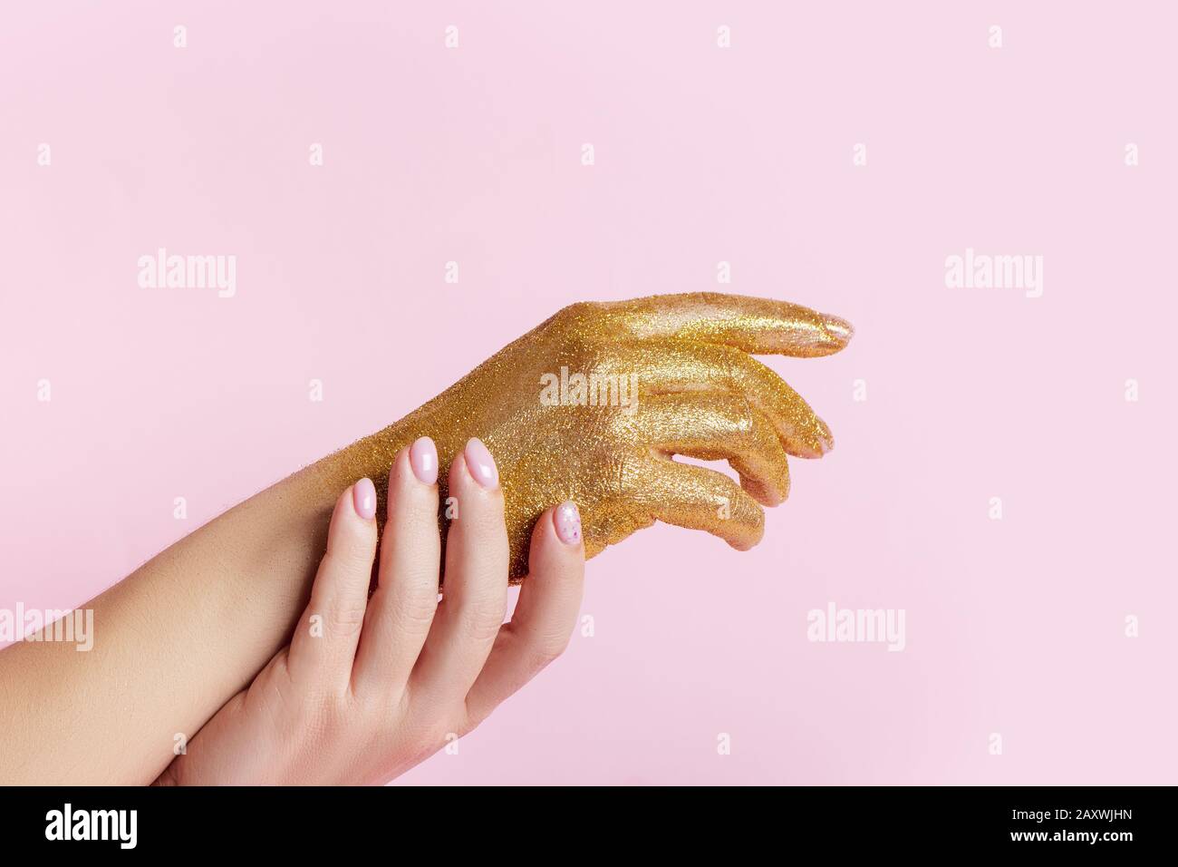 Perfekte Maniküre mit modischer Nagelkunst und Hand mit goldenem Glitter auf pinkfarbenem Hintergrund mit Kopierraum. Stockfoto