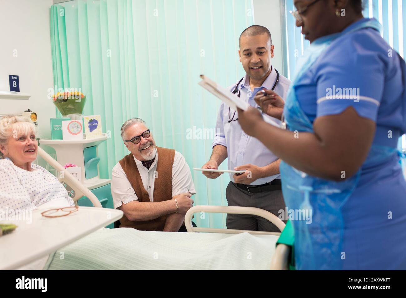 Arzt und Krankenschwester machen Runden und sprechen mit dem leitenden Patienten im Krankenhauszimmer Stockfoto