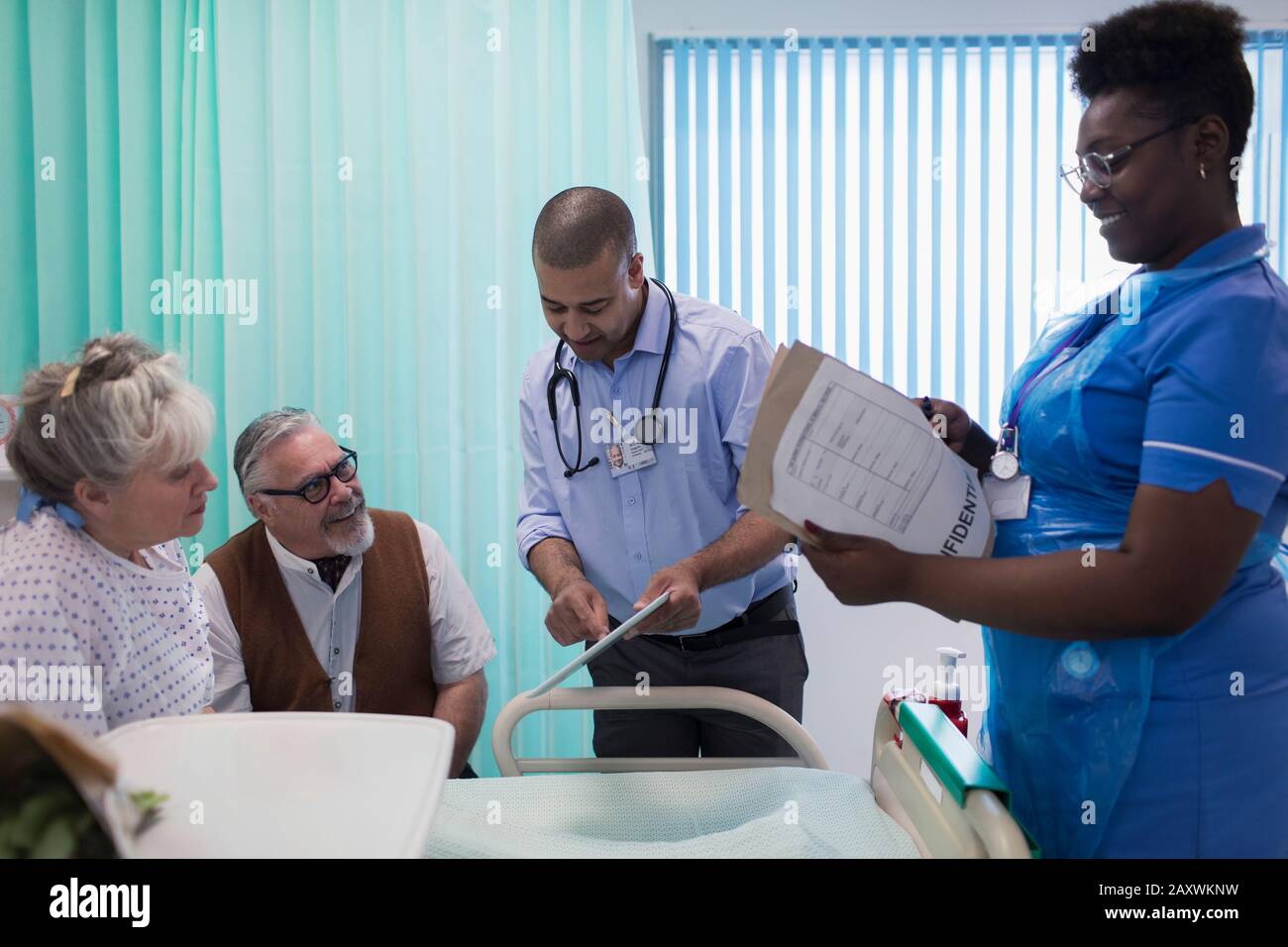 Arzt und Krankenschwester mit digitaler Tablette und medizinischer Dokumentation runden das Gespräch mit einem älteren Paar im Krankenhauszimmer ab Stockfoto