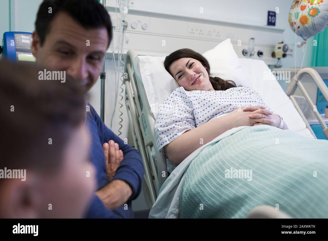 Lächelnder Patient, der mit der Familie im Krankenhauszimmer aufsucht Stockfoto