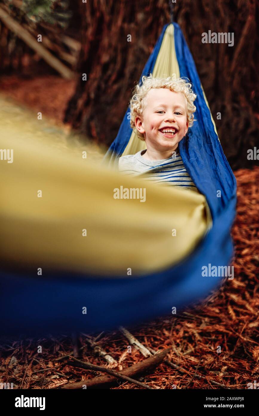 Lächelndes, lockiges Kind in einer Hängematte Stockfoto