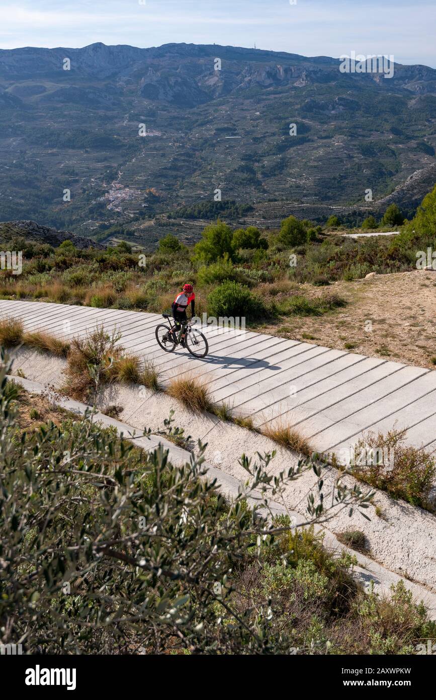 Mann mit dem Mountainbike-Rad auf einer konkreten Landstraße, Guadalest-Gebiet, Provinz Alicante, Costa Blanca, Spanien Stockfoto