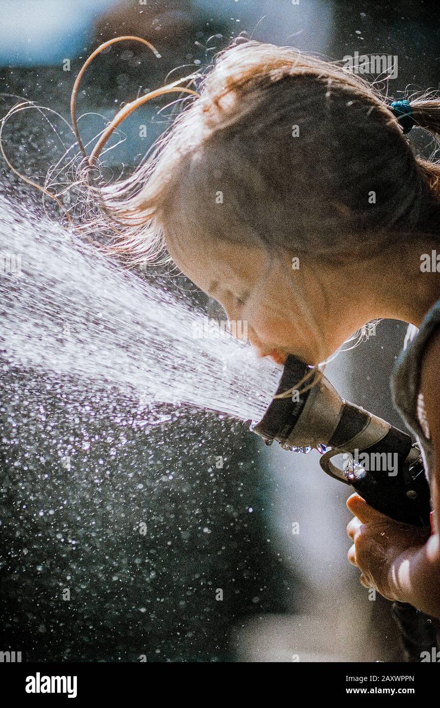Mädchen trinken am Schlauch an einem heißen Sommertag Stockfoto