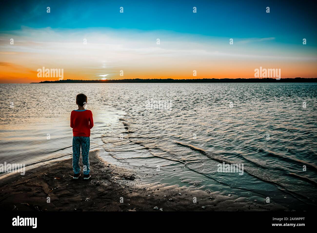 7 Jahre alter Junge, der an einem Sommertag den Sonnenaufgang beobachtet Stockfoto