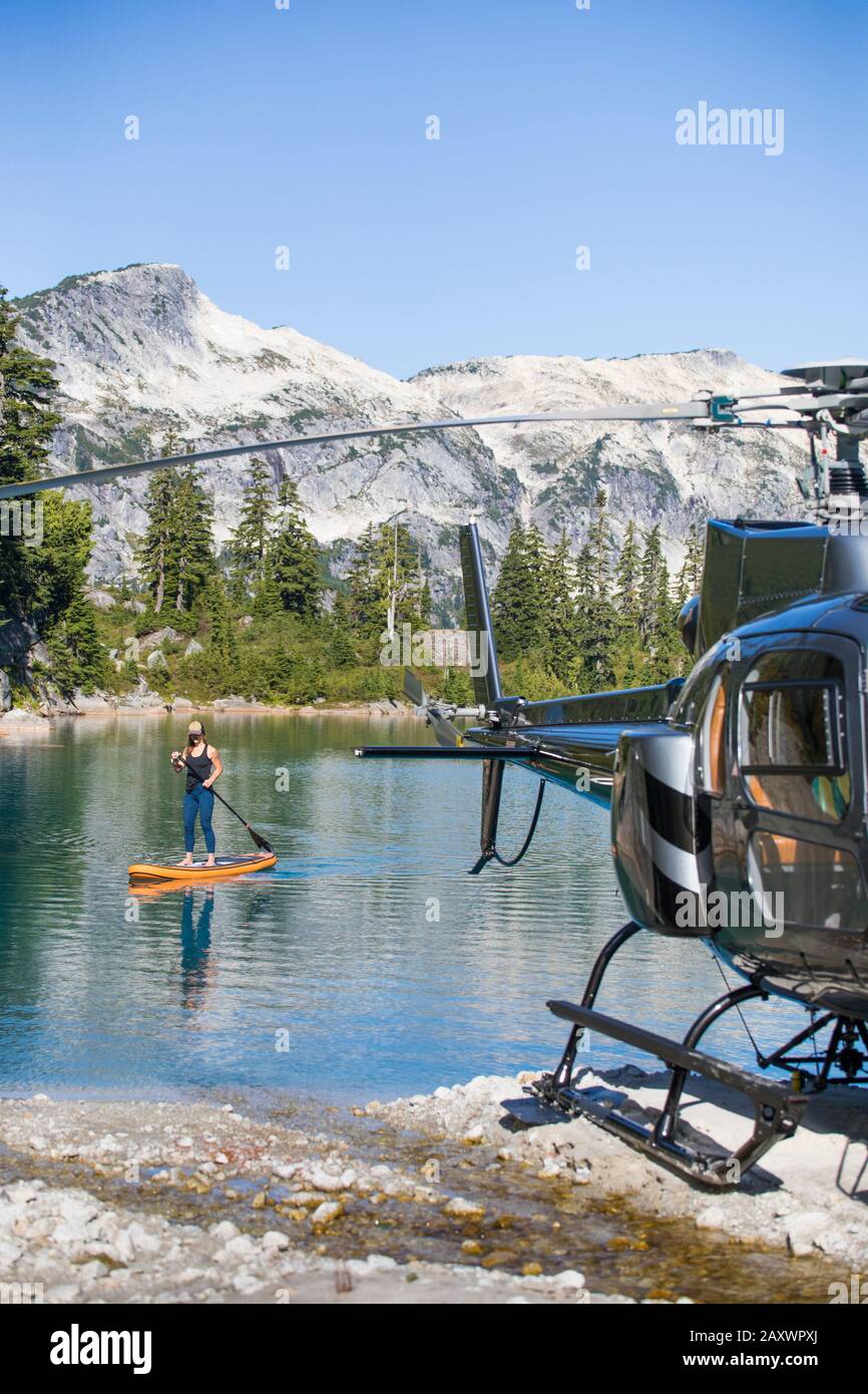 Aktive Frau Paddle Boards auf abgelegenen See mit dem Hubschrauber erreicht. Stockfoto