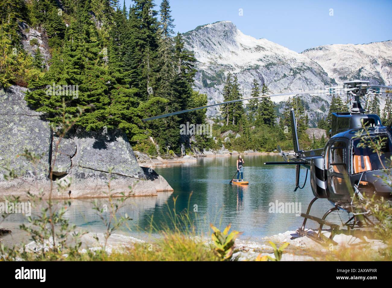 Aktive Frau Paddle Boards auf abgelegenen See mit dem Hubschrauber erreicht. Stockfoto