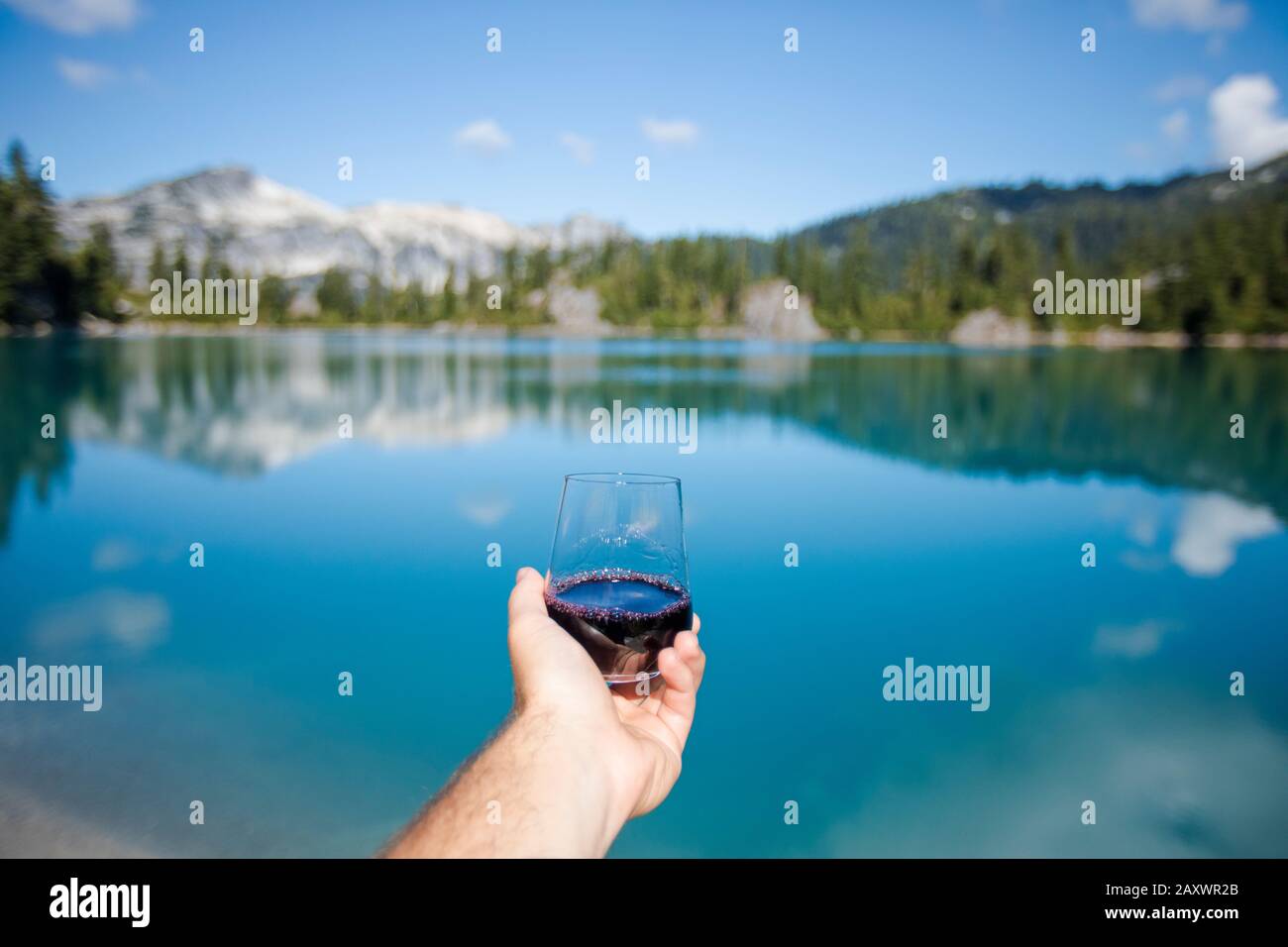 Genießen Sie ein Glas Rotwein am Bergsee. Stockfoto