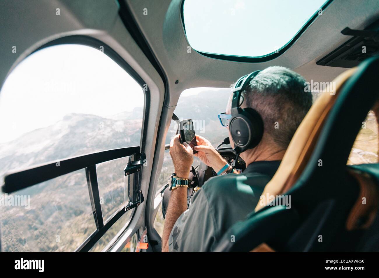 Pensionierter Mann fotografiert mit dem Telefon aus dem Hubschrauber. Stockfoto