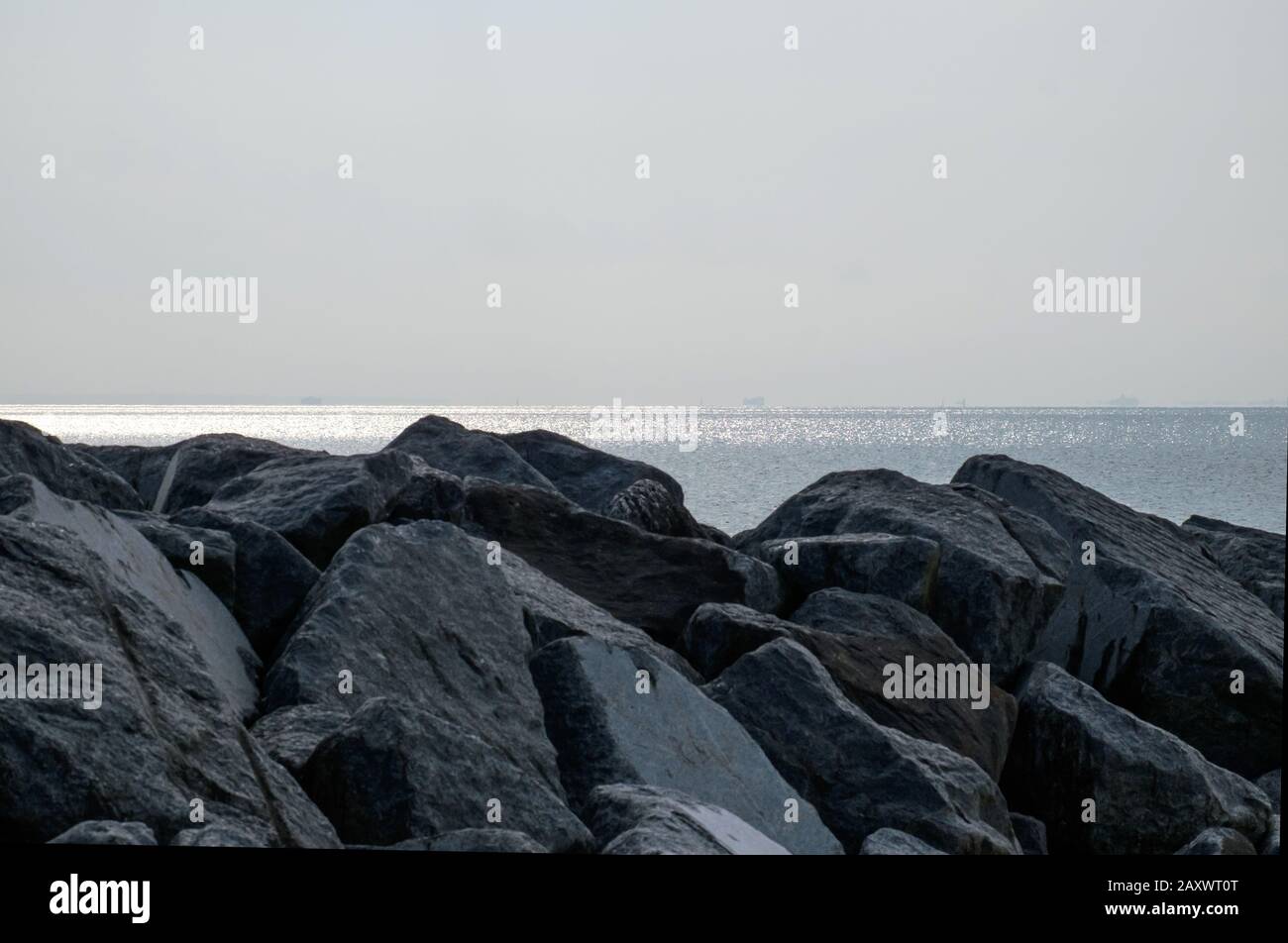 Felsen im Vordergrund mit Ozean und Horizont im Hintergrund, Frühabend-Sommer. Schöner Strand, West Sands Selsey, West Sussex, England. Stockfoto