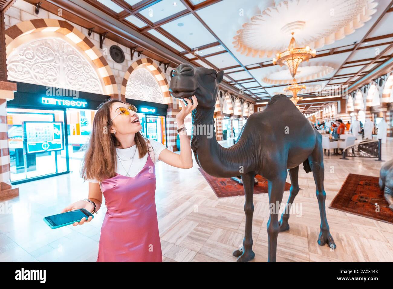 28. November 2019, VAE, Dubai: Touristenmädchen reibt lustige Kamelskulptur in der Dubai Mall Stockfoto