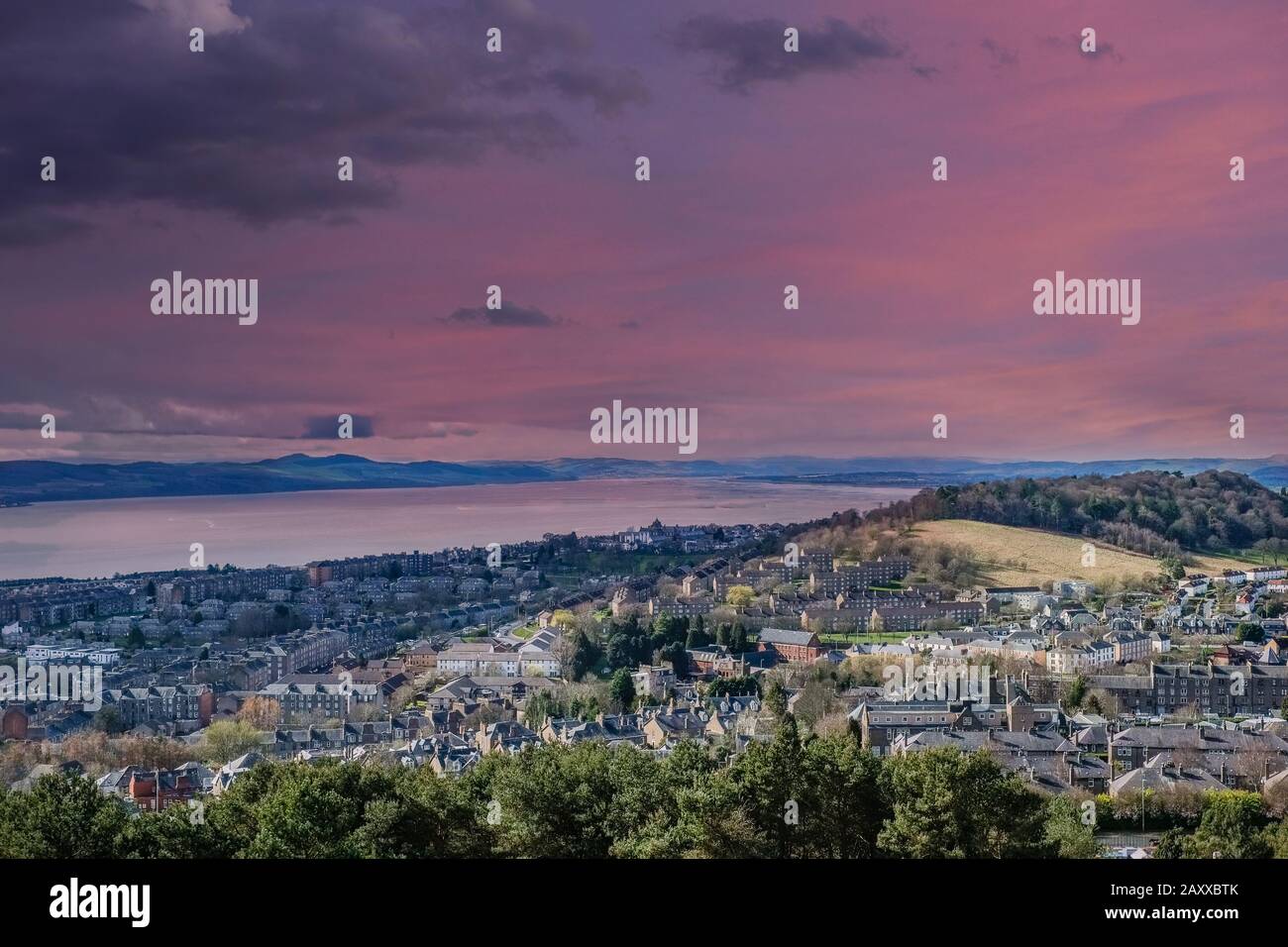 Blick vom Denkmal in Dundee Law hinab auf das Vierte der Tay Estuary in die weite, dunstige Entfernung, während die Sonne über die Stadt untergeht. Stockfoto