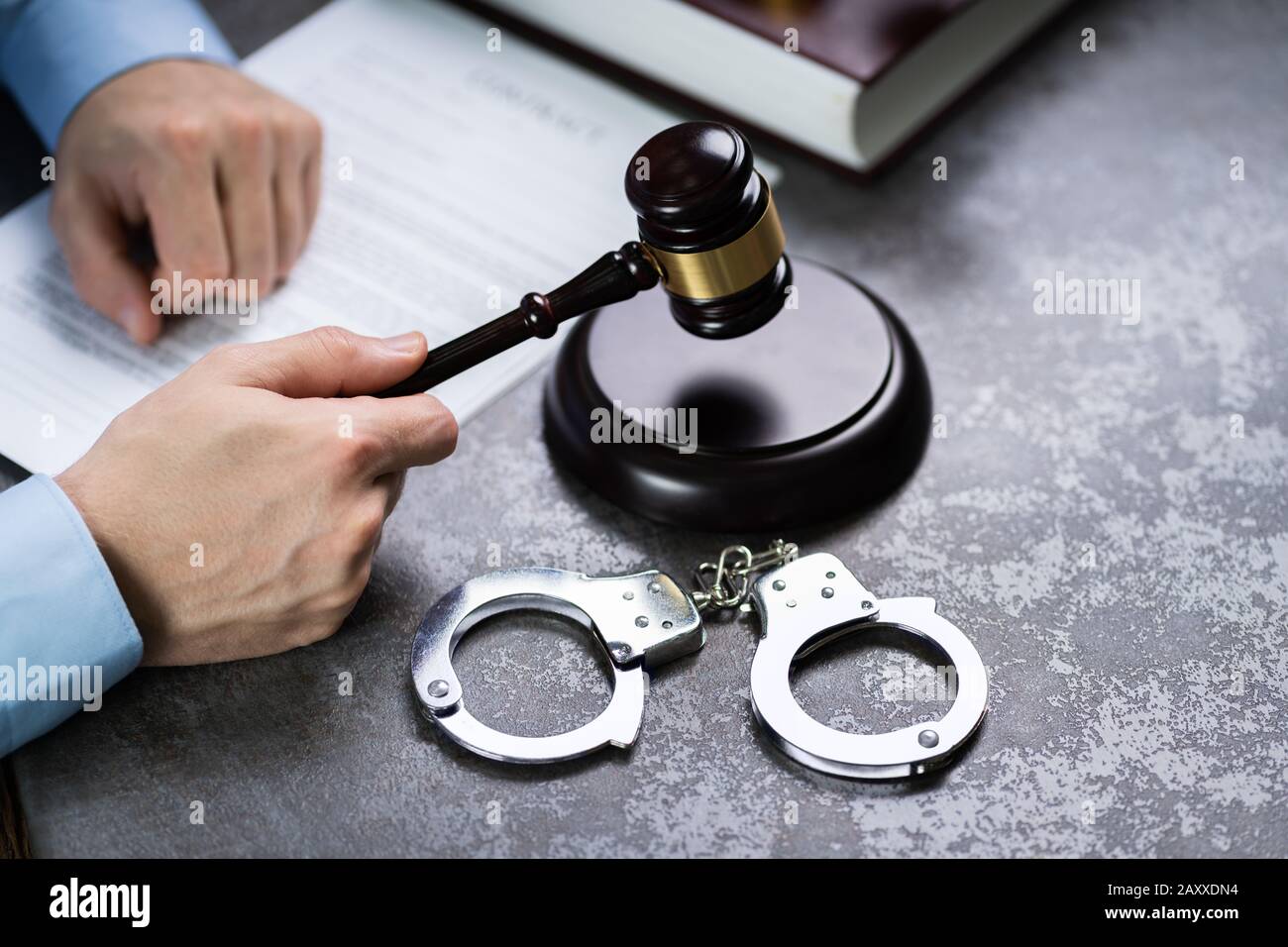Nahaufnahme eines Richters Hand markante Hammer mit Handschellen auf dem Schreibtisch im Gerichtssaal Stockfoto