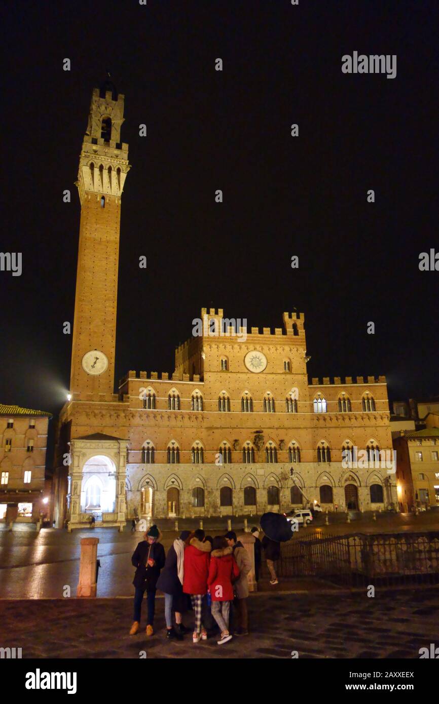 Siena bei Nacht. Piazza del Campo und Turm del Mangia beleuchteten.. Touristen auf dem Platz. Stockfoto