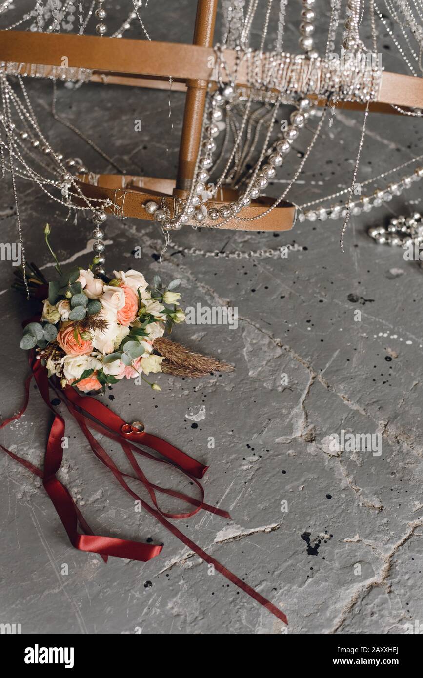 Ringe der Neuvermählten auf grauem Grunge und Hintergrund eines Blumenstraußes von Bräuten. Ringe und brautstrauß vor dem Hintergrund eines Chic, l. Stockfoto