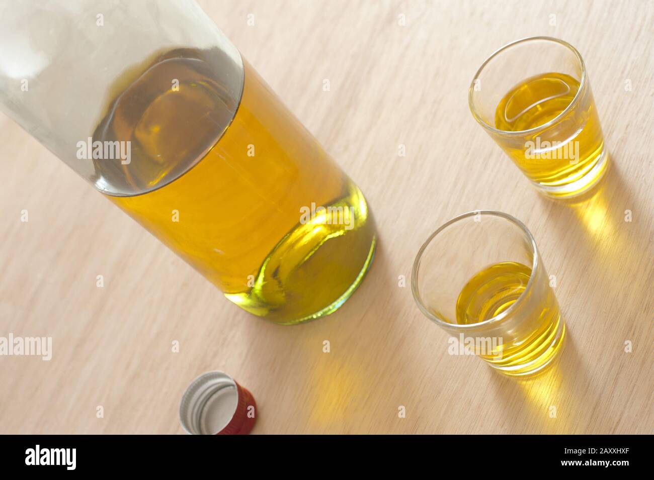 Spirituosen werden in Schussgläsern mit einer unbeschrifteten Flasche Alkohol serviert, möglicherweise Scotch oder Whisky in einem gekippten Winkel Stockfoto