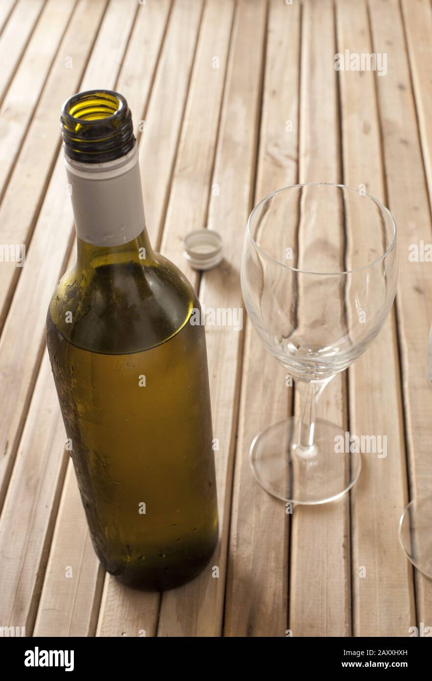 Öffnete eine unbeschriftete Flasche Weißwein, die stand, um zu atmen, und stand auf einem Holztisch mit zwei leeren Weingläsern, mit Copyspace Stockfoto