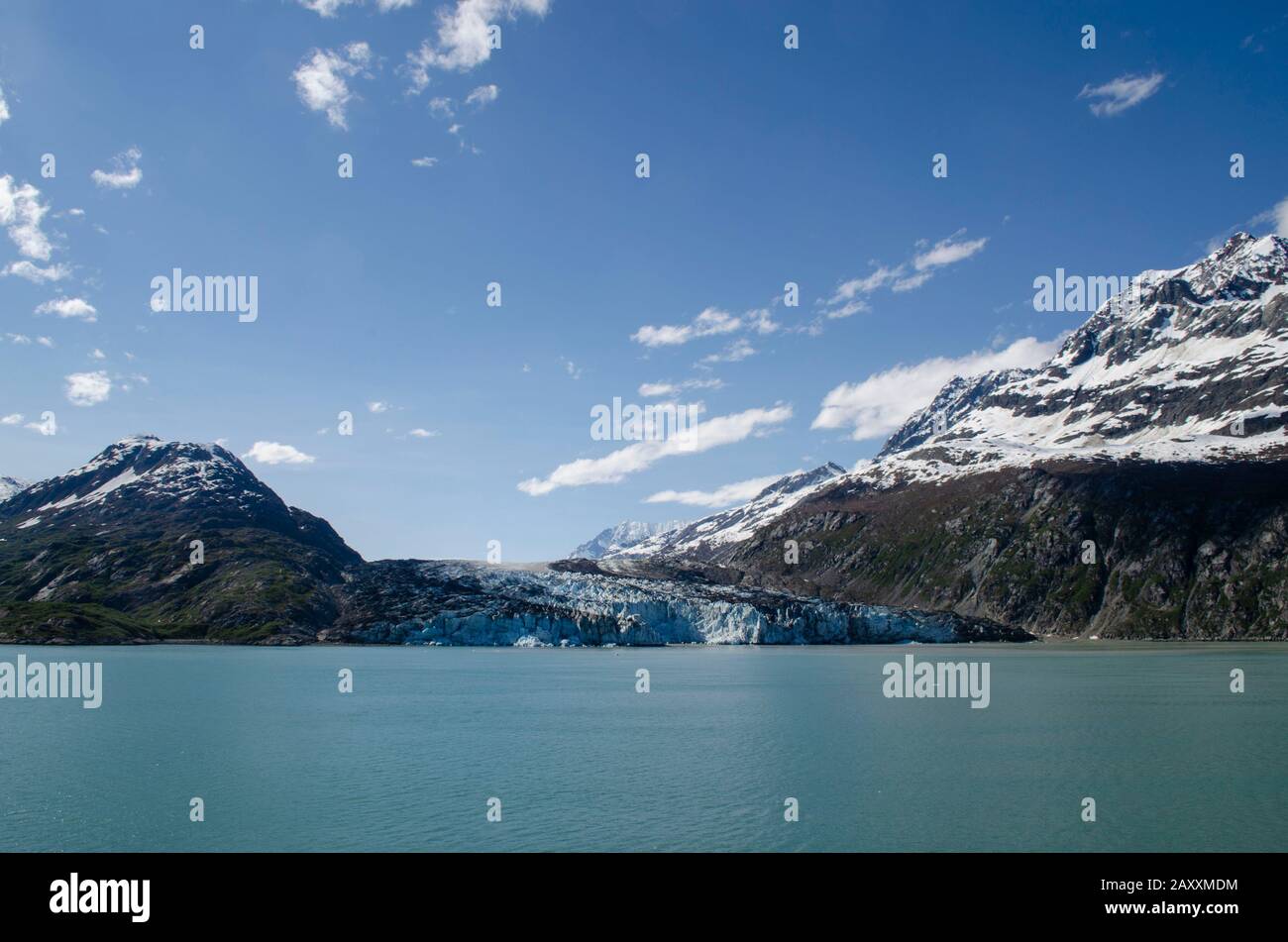 Glacier Bay, umgeben von zerklüfteten Bergen, spiegelt sich in den ruhigen Gewässern wider. Klarer Himmel, schneebewischte Gipfel, mit Gletschermeeren und reflektierenden Gewässern. Stockfoto