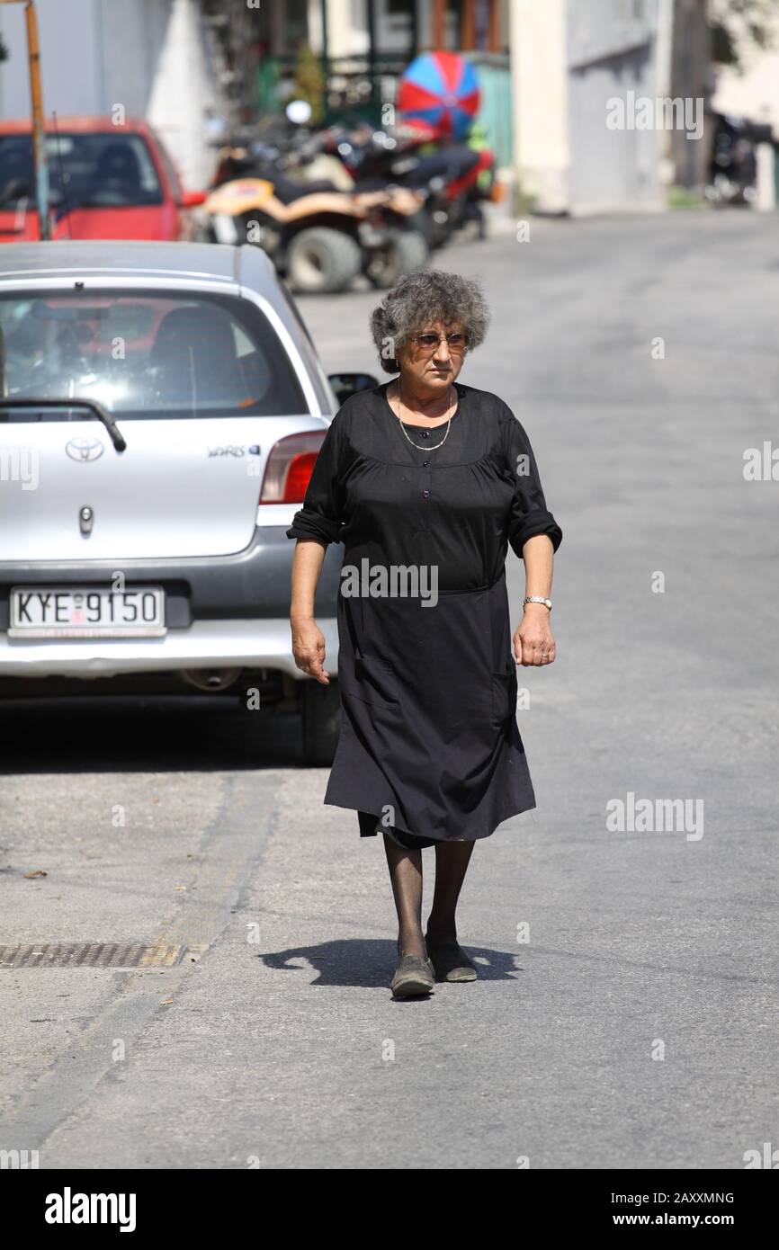 Die alte griechische Witwe läuft auf der Straße eines Dorfes Stockfoto