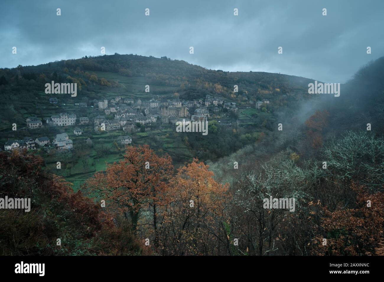 Nebel über dem mittelalterlichen Dorf, umgeben von Wald Stockfoto