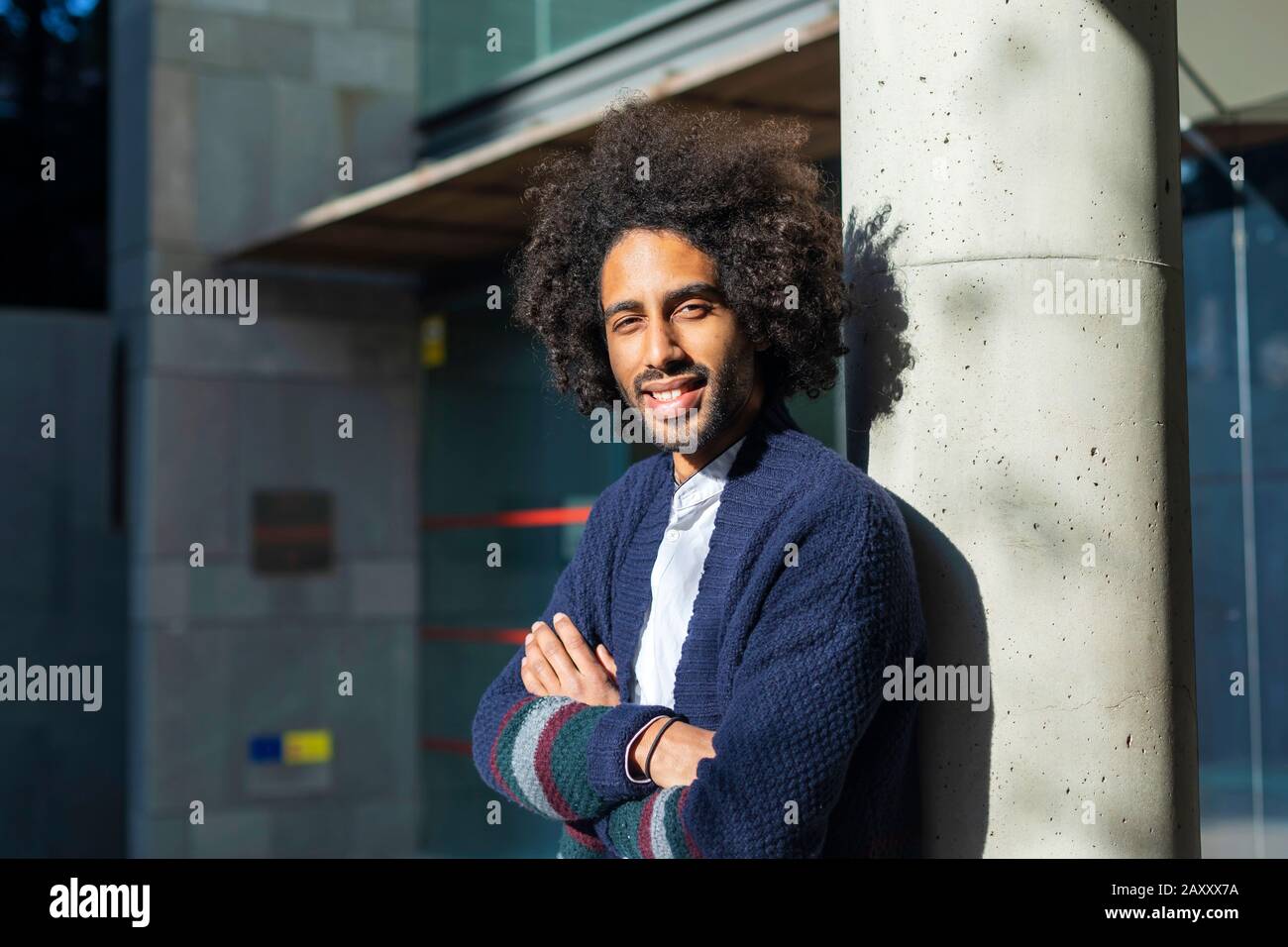 Ein junger, schöner, modischer afroamerikanischer Ständer steht in der Nähe einer Säule. Ein Jeans-Student und eine blaue Jacke mit modischer Frisur. Modische Jugend c Stockfoto
