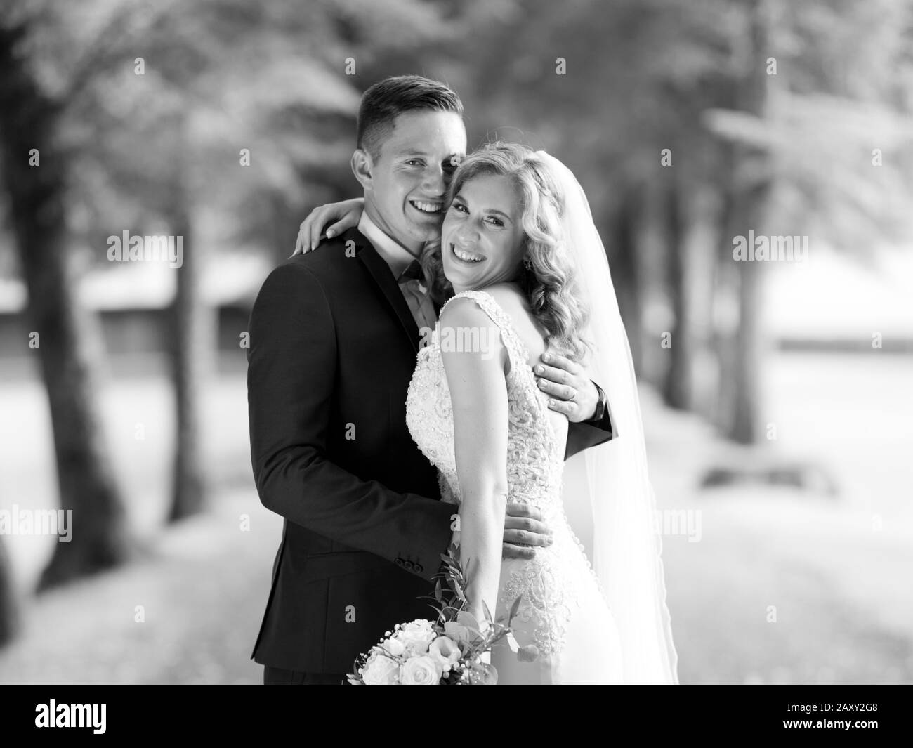 Brautpaar umarmte zärtlich beim Fotografieren im Park. Stockfoto