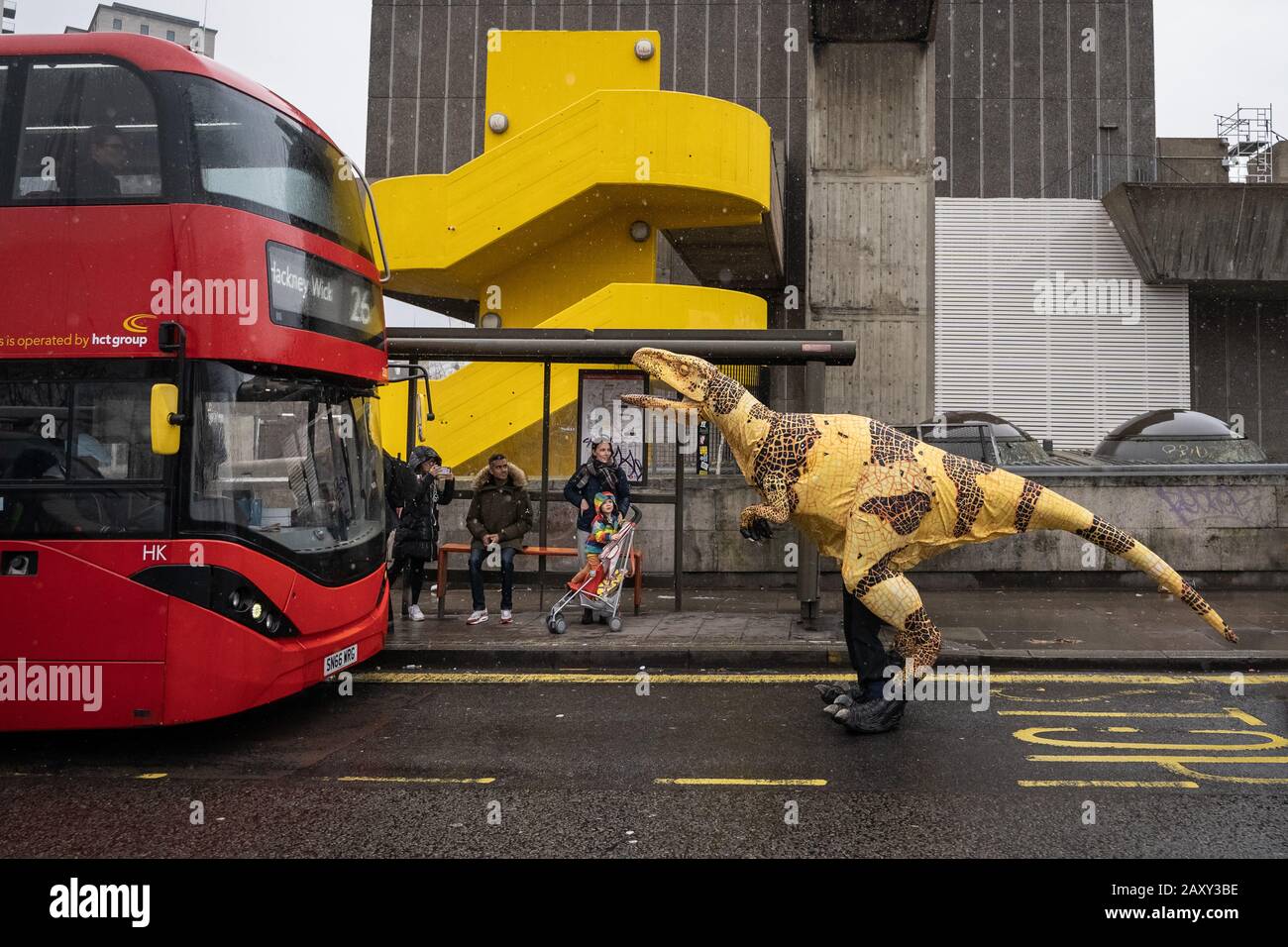 Eine lebensähnliche Dinosaurier-Marionette aus Velociraptor hält einen Bus auf der Waterloo Bridge als Werbestunt für den "Erth's Dinosaur Zoo", Southbank, London, Großbritannien Stockfoto