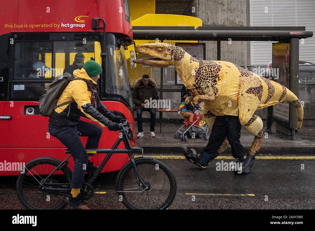 Eine lebensähnliche Dinosaurier-Marionette aus Velociraptor hält einen Bus auf der Waterloo Bridge als Werbestunt für den "Erth's Dinosaur Zoo", Southbank, London, Großbritannien Stockfoto