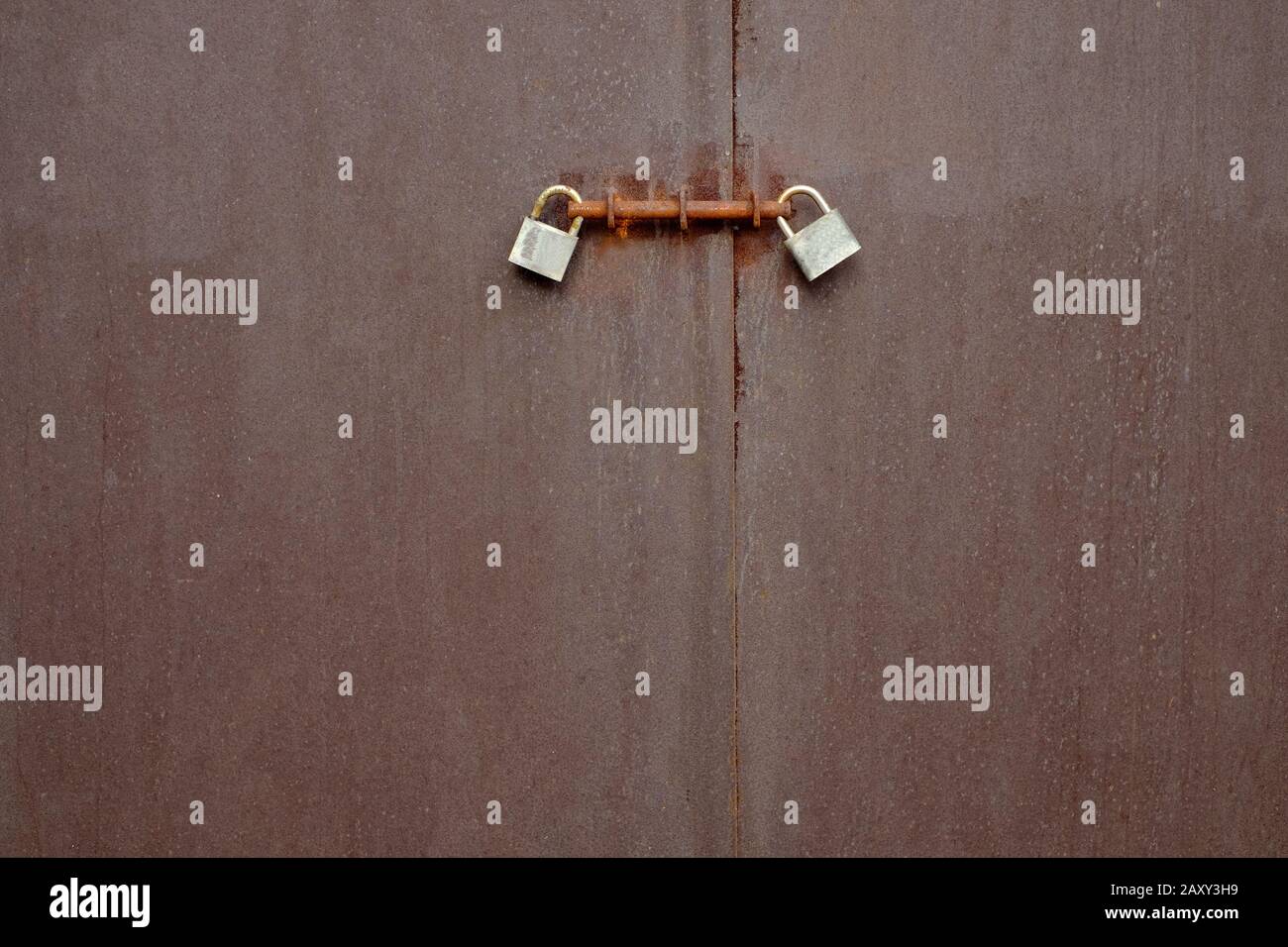 Doppelte Paddlocks und Schrauben, fest geschlossene Tür, Riemen und Zahnspange. Stockfoto