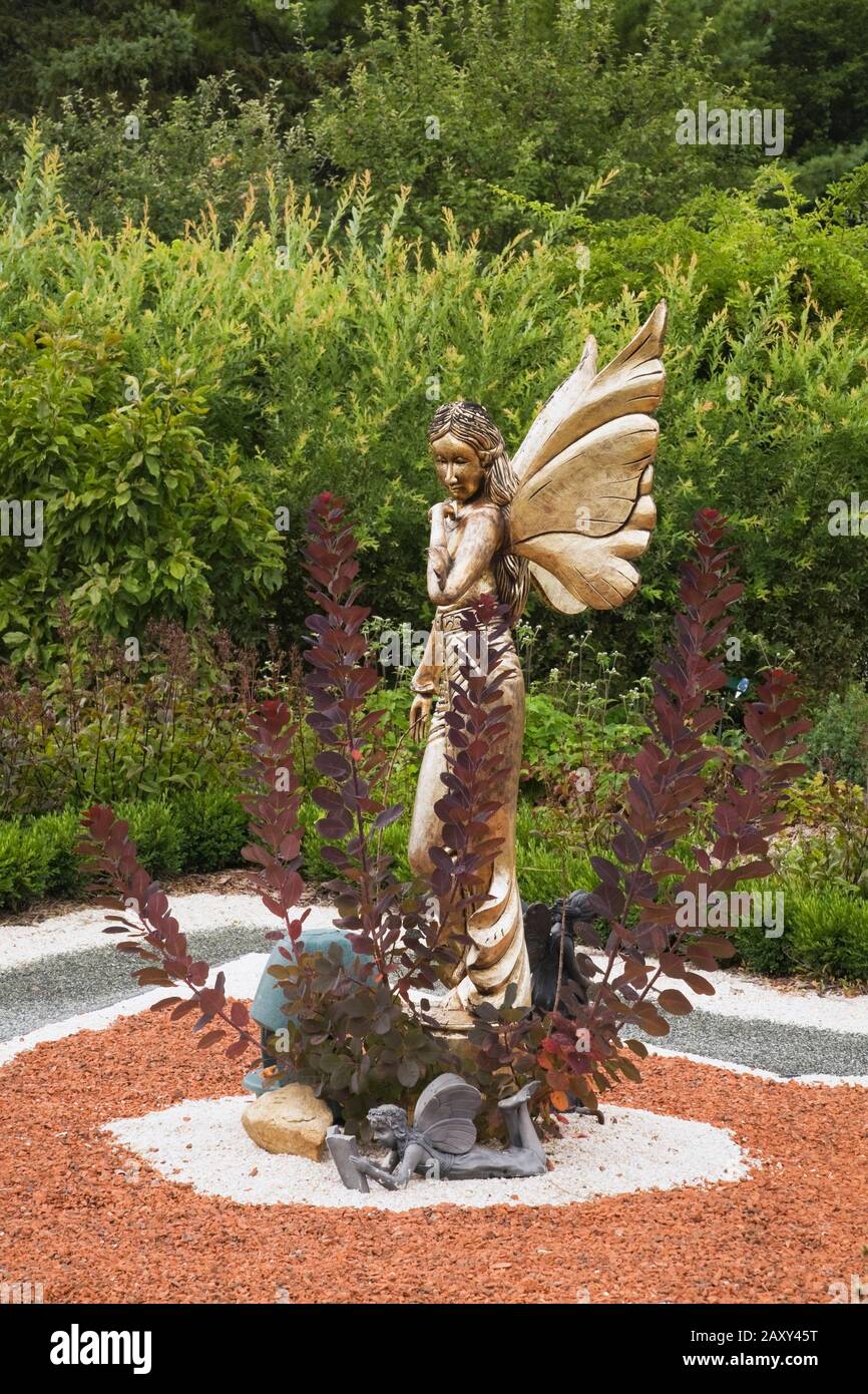 Statue einer goldenen geflügelten Fabelfee auf Sternenform Parterre im Märchengarten im Sommer an der Route des Gerbes d'Angelica Garten im Sommer. Stockfoto