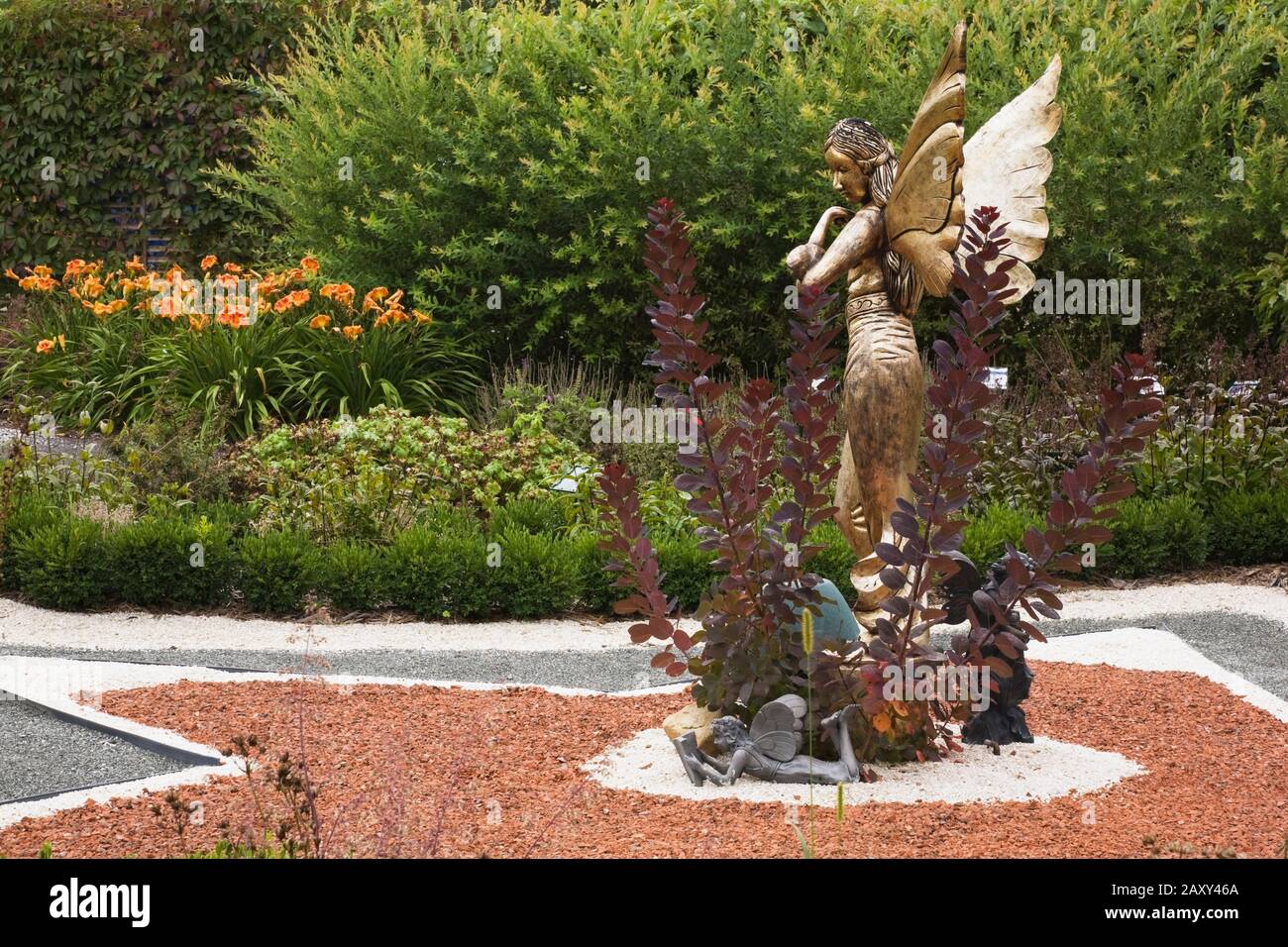 Statue einer goldenen geflügelten Fabelfee auf Sternenform Parterre im Märchengarten im Sommer an der Route des Gerbes d'Angelica Garten im Sommer. Stockfoto