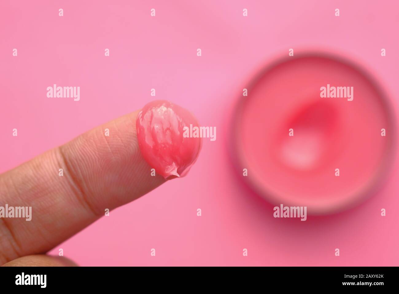 Nahaufnahme von Vaseline bei Frauen Finger auf pinkfarbenem Hintergrund Stockfoto
