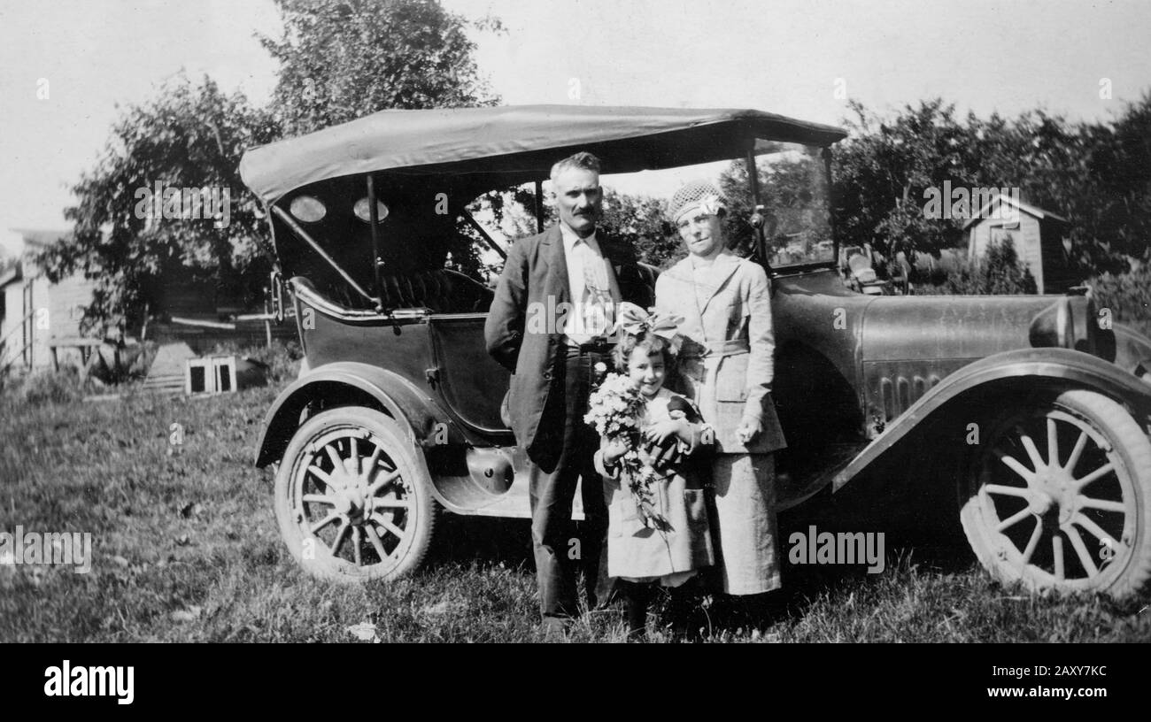 Großmutter und Großvater posieren vor ihrem Auto mit Enkelin, ca. 1928. Stockfoto