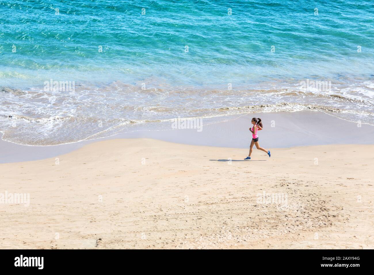 Läufer, der am Strand am Meer läuft - Blick von oben. Frau Athletin trainiert Cardio Jogging beim morgendlichen Workout. Hero Shot, viel Copyspace. Stockfoto