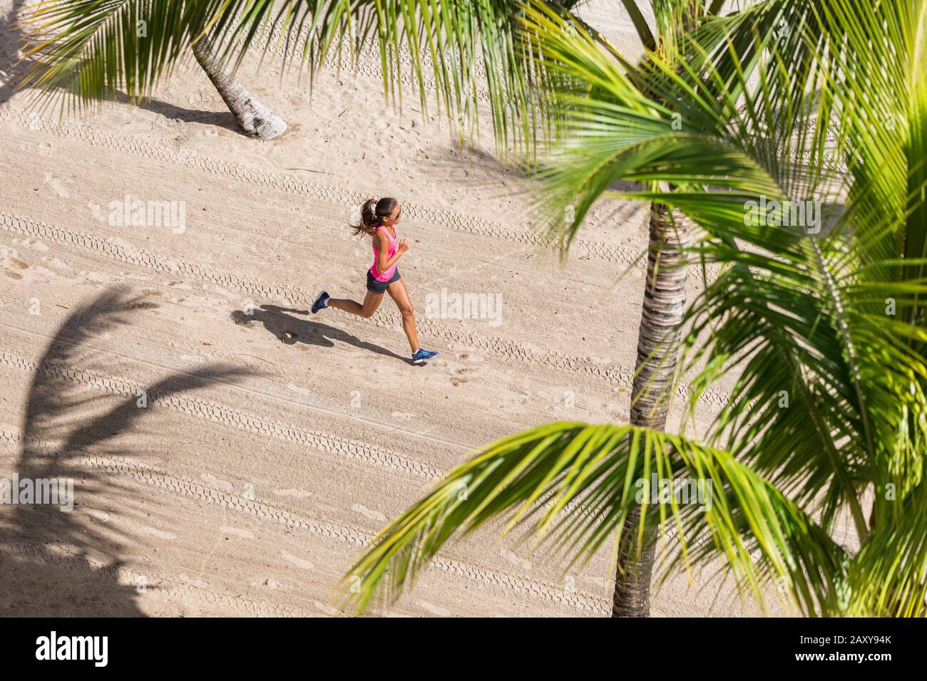 Fitness-Athlet Lauftraining Cardio am Strand. Frau, die zwischen Palmen rüttelt. Blick von oben auf den Boden und den Sand. Gesundheits- und Sportkonzept. Copyspace. Stockfoto