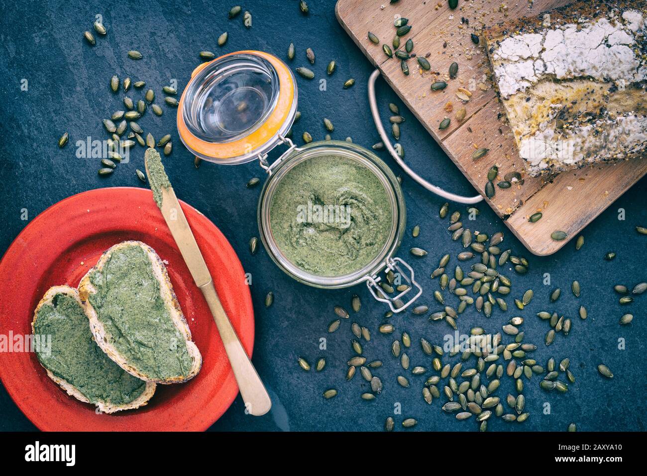 Hausgemachte vegane Kürbissaatbutter in einem kilner Glas und auf einem weißen Sauerteig Brot auf einem Schiefergrund verteilt Stockfoto