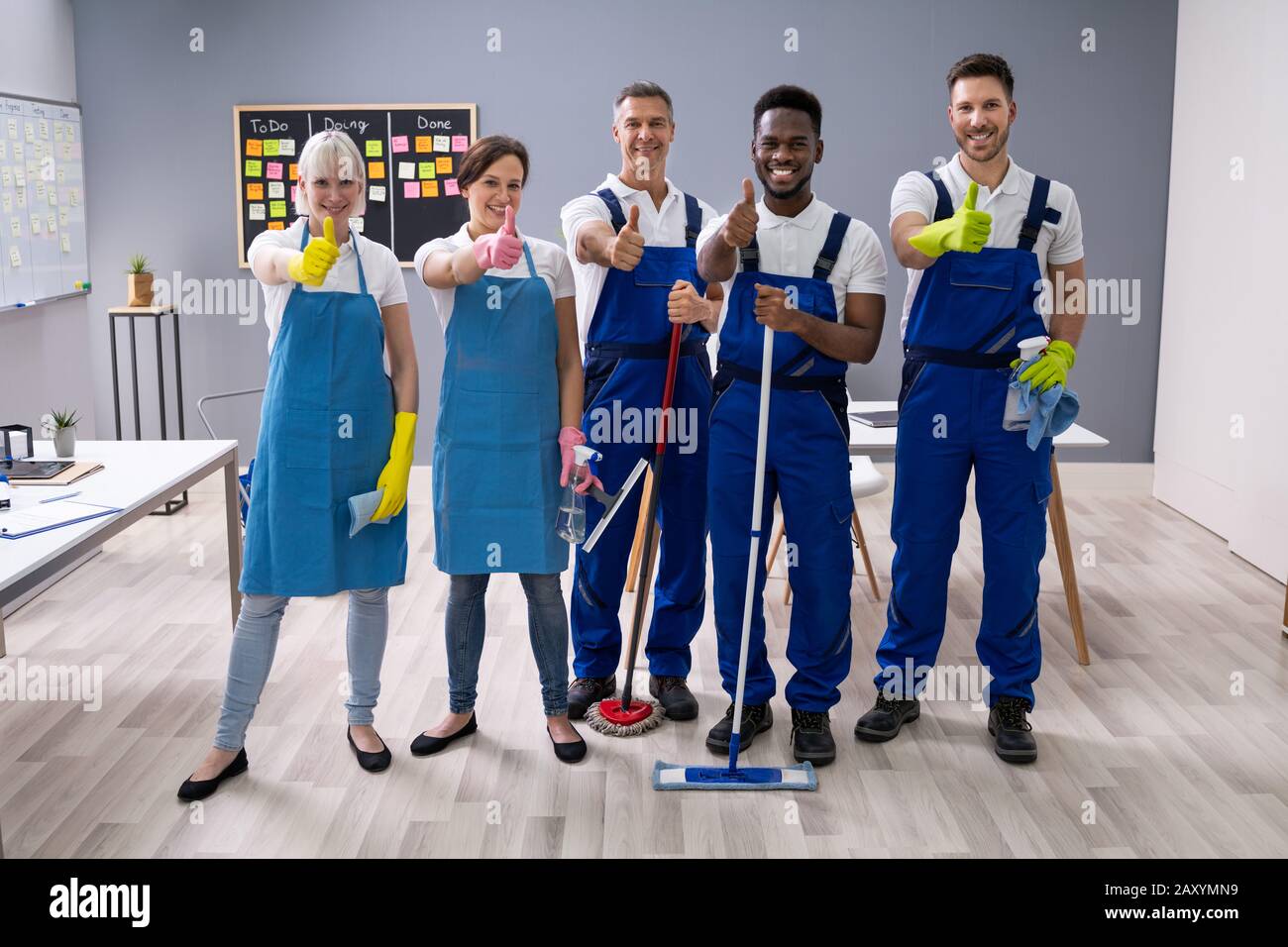 Portrait von Happy Diverse Hausmeister im Büro mit der Reinigung der Ausrüstung zeigen Daumen Anmelden Stockfoto