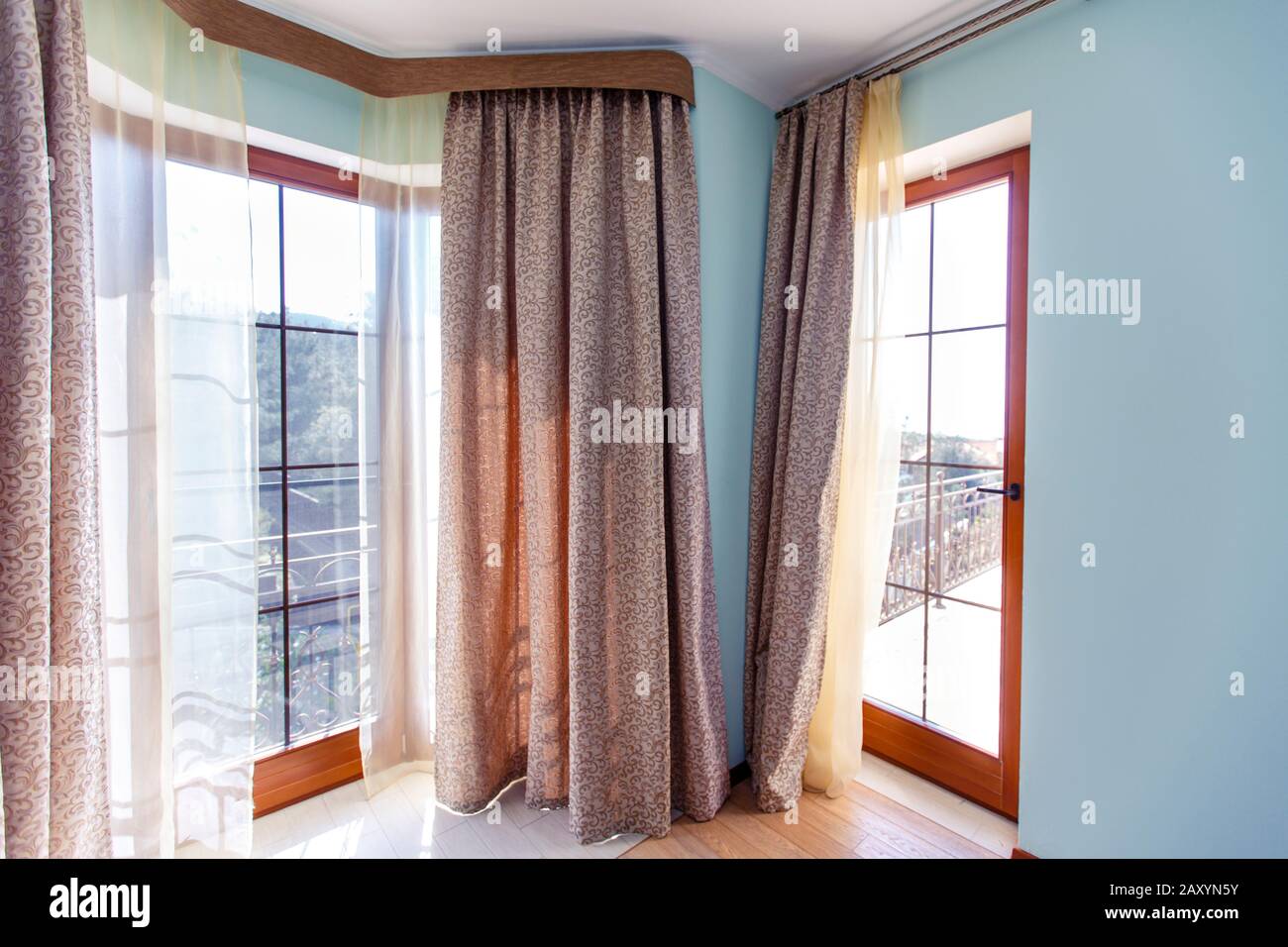 Große Fenster mit Vorhängen. Die Wände sind blau. Braune Vorhänge. Stockfoto