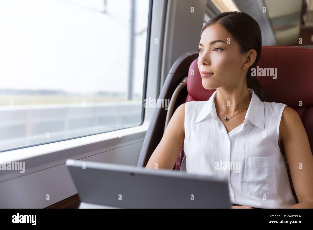 Asian Woman mit Laptop im Zug unterwegs. Geschäftsfrau, die auf dem Arbeitsweg auf dem Computer arbeitet, um das Fenster zu betrachten, ist bereit, auf die Arbeit zu gehen. Stockfoto