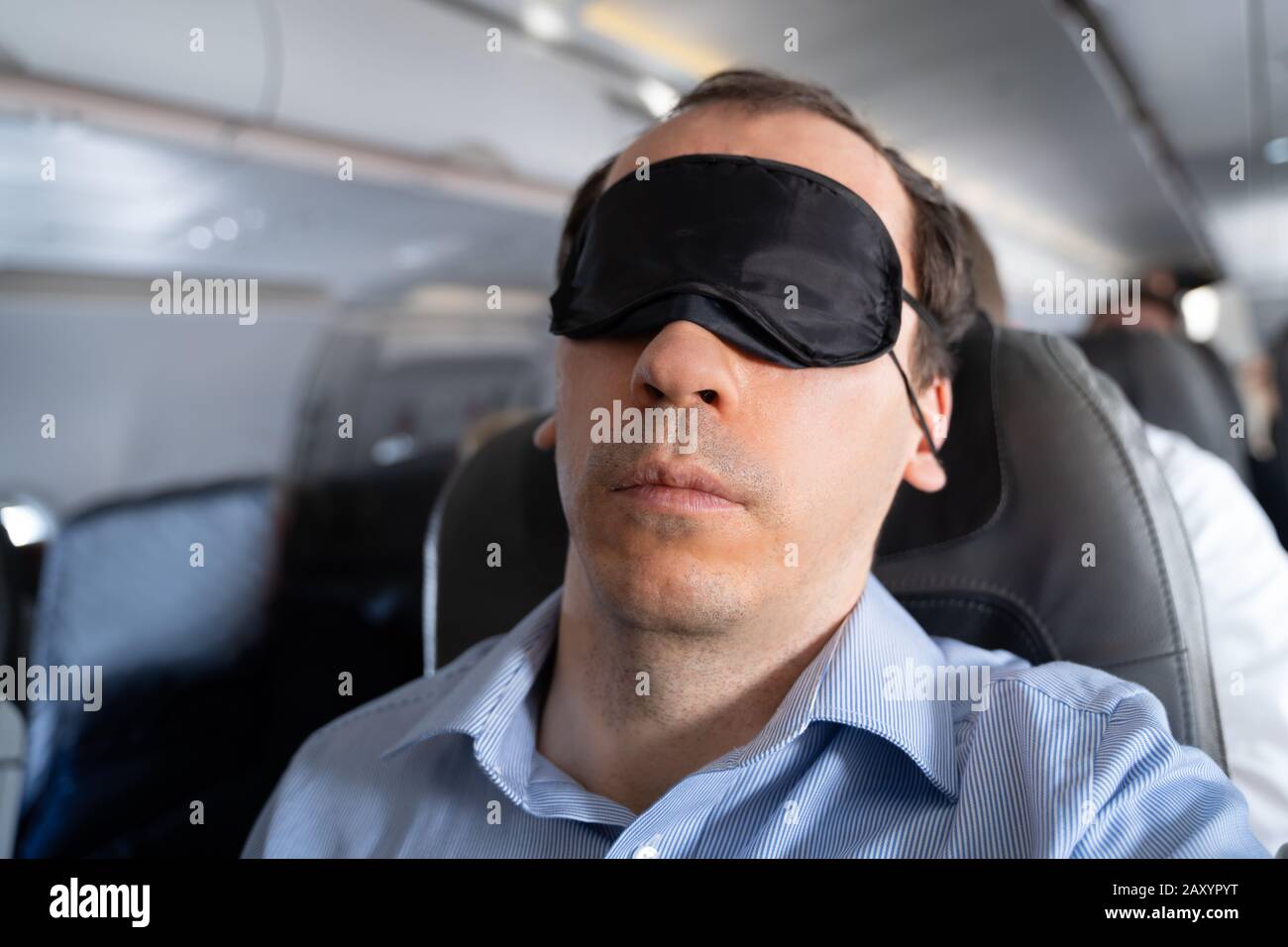 Junger Mann Schläft Mit Schlafmaske Im Flugzeug Stockfoto