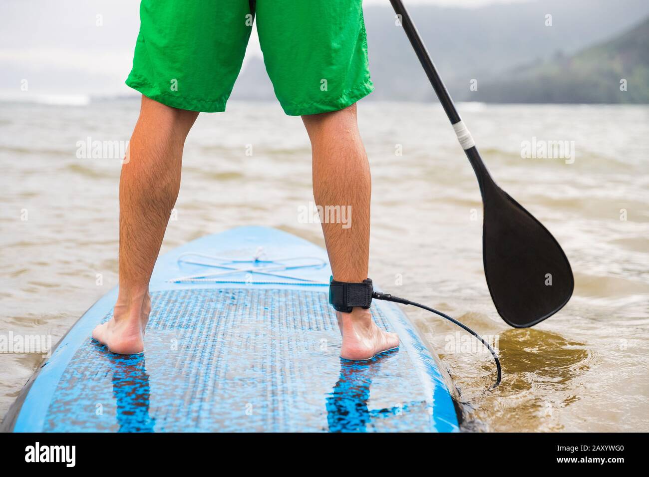 Paddleboard-Mann paddelt auf dem SUP Stand Up Paddle Board am See. Nahaufnahme von Füßen und Beinen. Stockfoto
