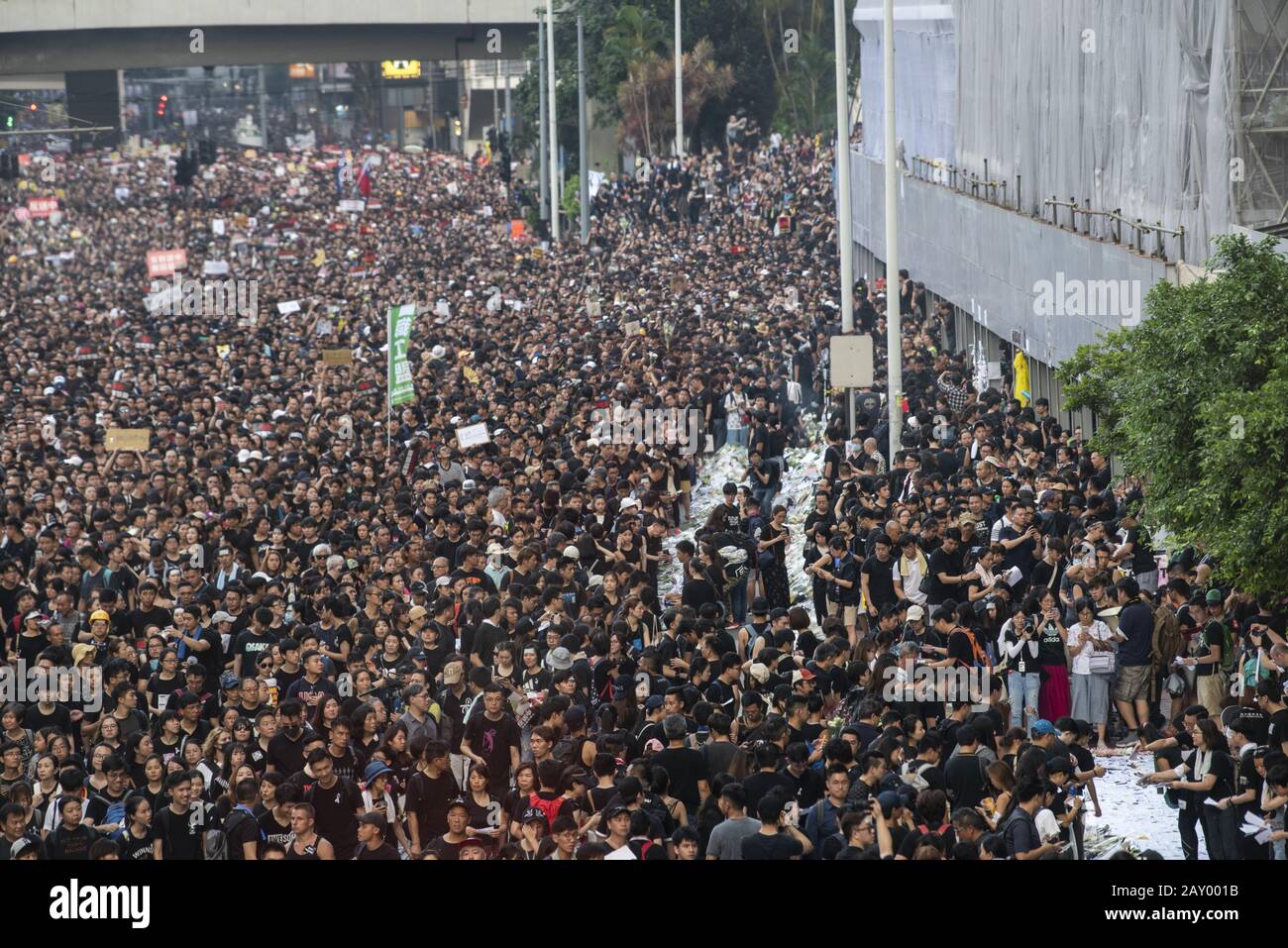 Hongkong, Hongkong SAR, China. Juni 2019. Der protestmarsch passierte und Blumen in einer Gedenkstätte im Einkaufszentrum Pacific Place in der Admiralität an einen Protestler namens Regencoat man legte nach Eröffnung eines Protestbanners auf dem Gebäude zu seinem Tod. Der Standort wurde zum Schwerpunkt für den marsch in Hongkong gegen das Auslieferungsgesetz von Hauptgeschäftsführer Carrie Lam. Die Aufhebung der Rechnung unterbricht den marsch. Credit: Jayne Russell/ZUMA Wire/Alamy Live News Stockfoto