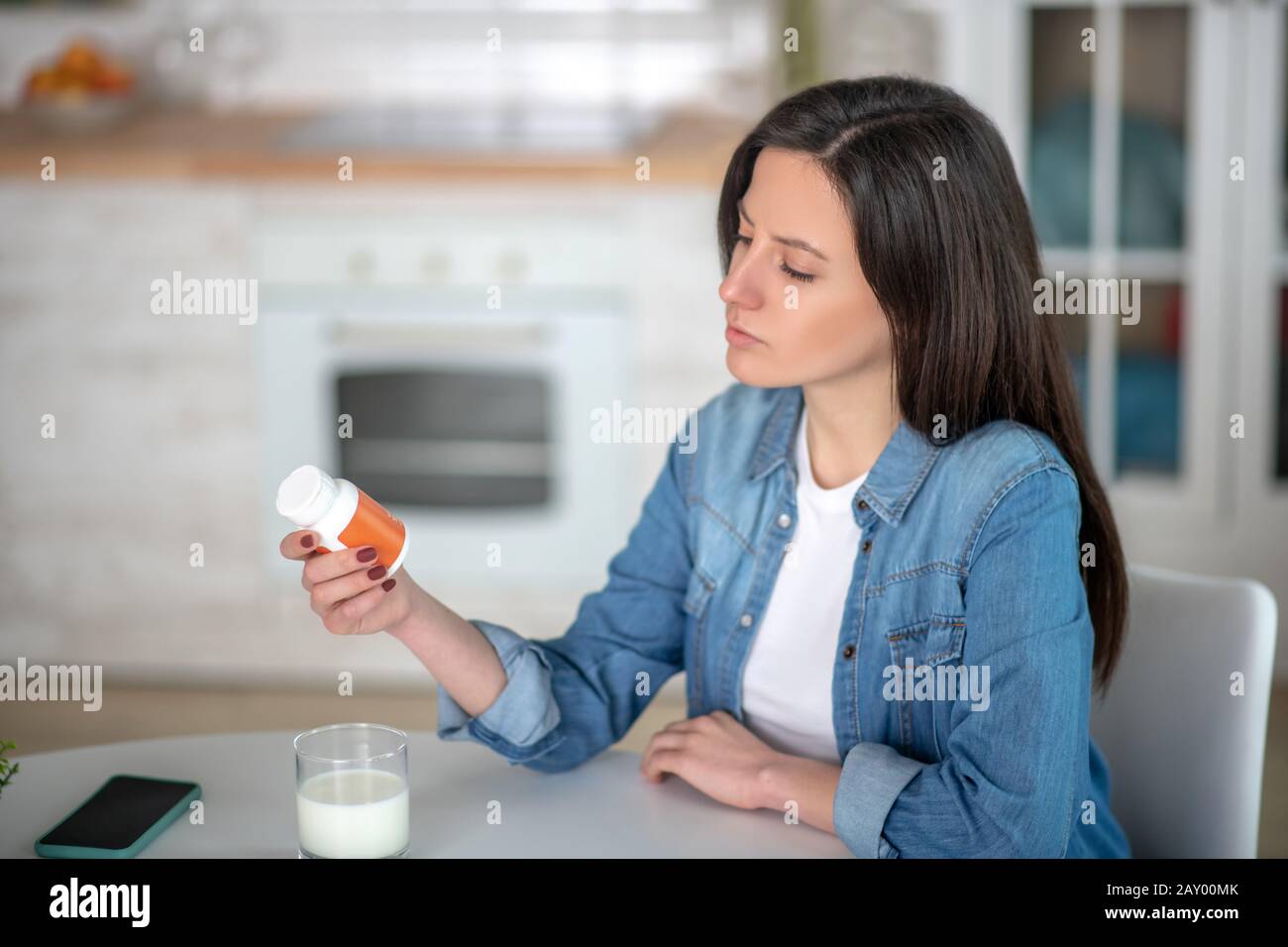 Schwarz-haariger Womn mit Blick auf den Pillenbehälter Stockfoto